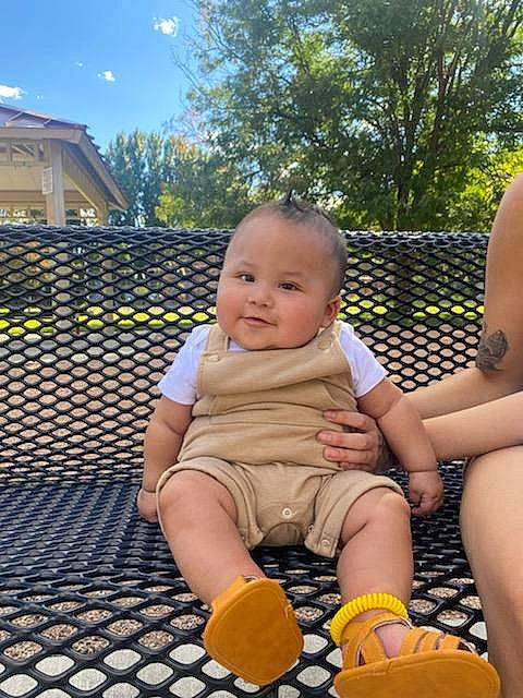 Legend is registered to the contest to win money with this photo: baby, child, flooring, football, fun, grass, happy, human_leg, joy, lap, leg, leisure, people_in_nature, person, recreation, shorts, sitting, sky, summer, thigh