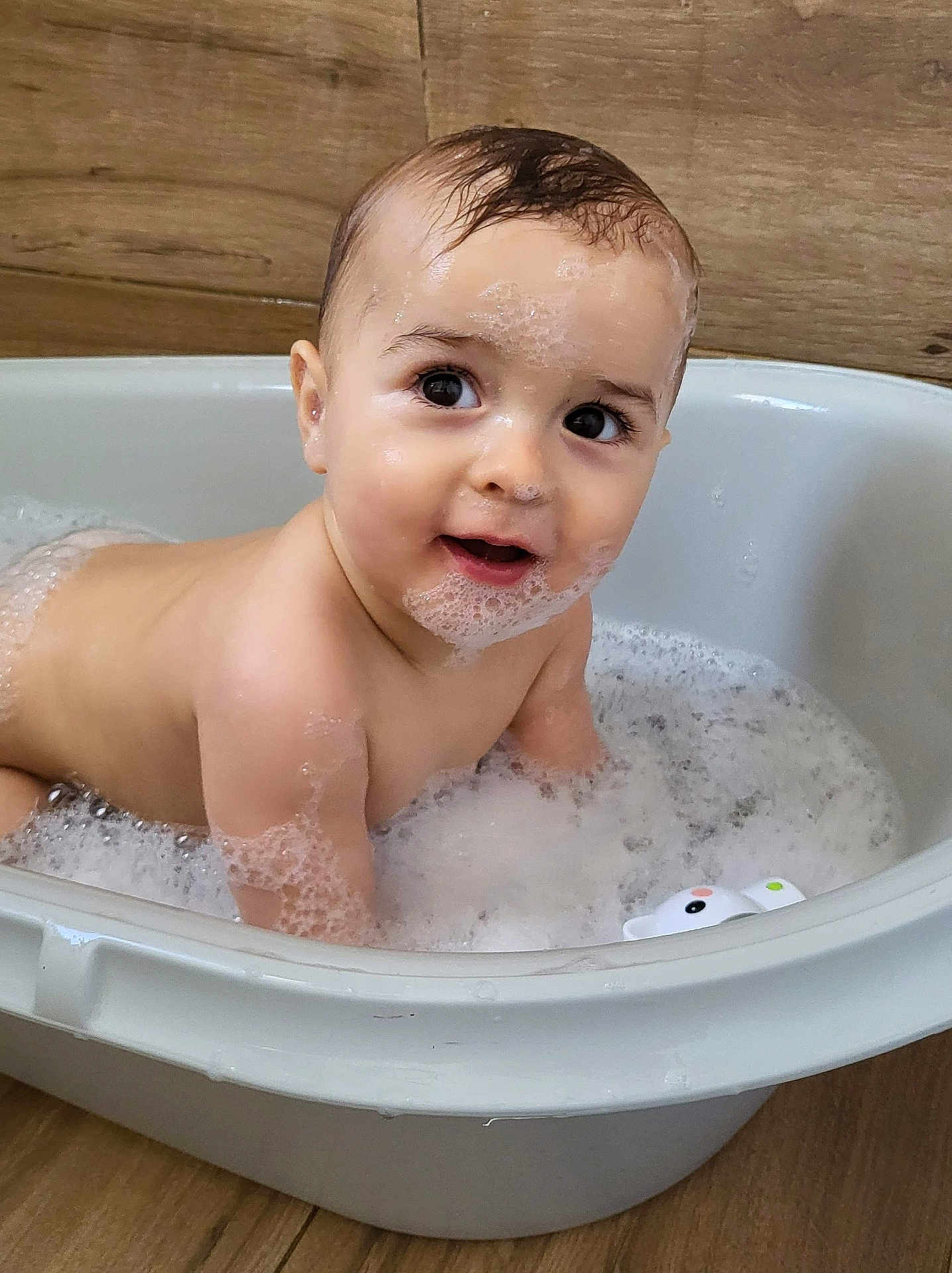 Raphaël participe au concours pour gagner de l'argent avec cette photo : baby, bathtub, foam, bubbles, child, face, water, wooden_floor, skin, cute, happy, bath_time, playing, wet_hair, sudsy, infant, smiling, indoors, toy, cleaning
