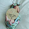 newborn, baby, infant, sleeping, blanket, headband, floral_pattern, sign, announcement, cute, wrapped, feet, hand, white_bedding, portrait, peaceful, soft_light, indoors, child, person