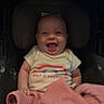 baby, car_seat, smiling, blanket, infant, clothing, happy, child, person, indoors, seat, cute, portrait, young_child, cozy, apparel, car_interior, human, sitting, expression