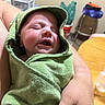 Jasper is registered to the contest to win money with this photo: baby, sleeping, green_towel, wrapped, arms, indoor, table, hand, peaceful, child, person, blanket, furniture, cozy, newborn, portrait, infant, soft, relaxed, home