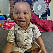 Noah joined the competition — help win amazing prizes! toddler, child, smiling, indoor, sitting, shirt, shorts, suspenders, hair_pigtails, carpet, fan, blanket, furniture, television, happy, cute, person, home, room, playful