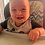 baby, high_chair, smiling, food, messy, bib, child, face, hand, teeth, indoor, light, window_blinds, clothing, person, cute, happy, infant, feeding, portrait