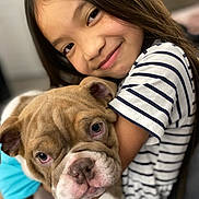 Lunasaurus is registered to the contest to win money with this photo: child, dog, bulldog, puppy, smiling, hugging, striped_shirt, long_hair, portrait, close_up, indoor, pet, cute, affection, love, face, animal, person, young, friendly