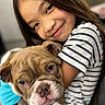 affection, animal, bulldog, child, close_up, cute, dog, face, friendly, hugging, indoor, long_hair, love, person, pet, portrait, puppy, smiling, striped_shirt, young