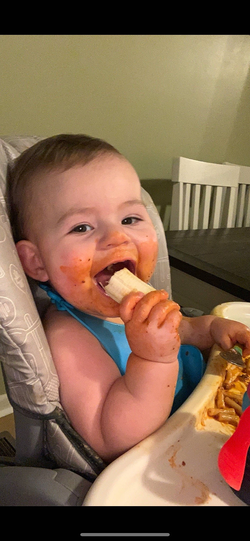 Harper is registered to the contest to win money with this photo: baby, biting, chair, cheek, finger, food, food_craving, gesture, happy, human_body, jaw, leg, lip, mouth, nail, nose, person, skin, tableware, thumb