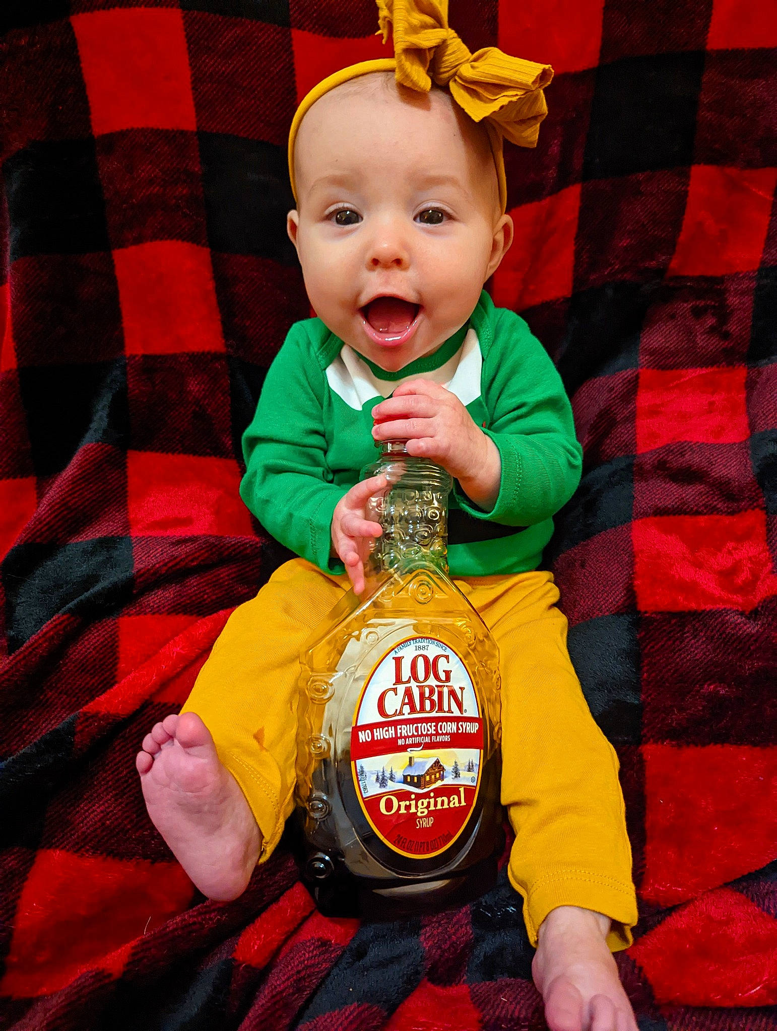 Hannah is registered to the contest to win money with this photo: baby, baby_toddler_clothing, child, event, face, facial_expression, fictional_character, fun, happy, human, orange, person, plaid, red, sleeve, smile, standing, surprise, t_shirt, tartan