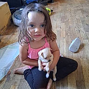 Eliyanah Mae is registered to the contest to win money with this photo: child, puppy, floor, wooden_floor, pink_top, wet_hair, sitting, indoor, furniture, shoe, dog, pet, cute, young_child, home, casual, person, animal, holding, relaxed
