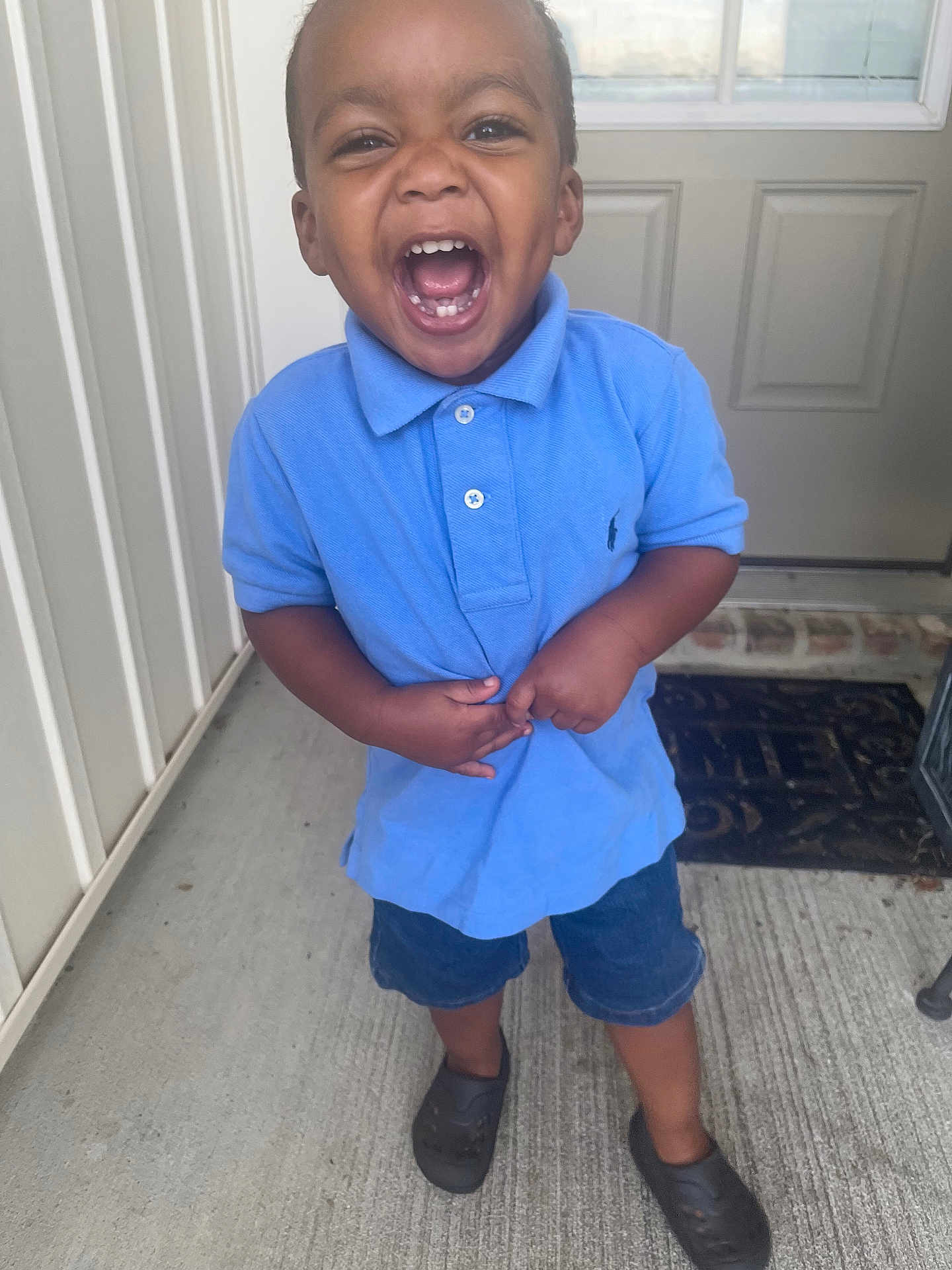 Jayjay joined the competition — help win amazing prizes! toddler, child, boy, smiling, laughing, blue_shirt, denim_shorts, porch, door, welcome_mat, concrete_floor, casual_clothing, shorts, footwear, black_shoes, happy, joyful, outdoor, person, young_child