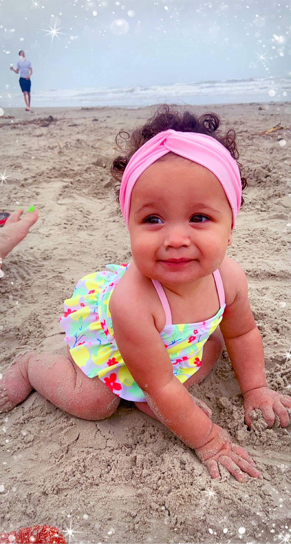 Kira is registered to the contest to win money with this photo: baby, baby_toddler_clothing, beach, body_of_water, fun, happy, hat, headwear, joy, leisure, people_in_nature, people_on_beach, person, pink, play, recreation, sand, smile, swimwear, thigh
