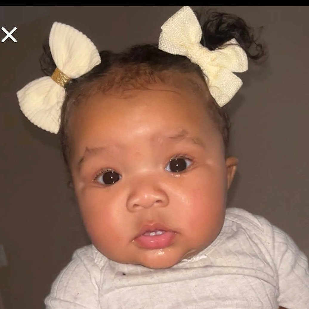 Mia is registered to the contest to win money with this photo: baby, child, face, hair_bow, cute, portrait, infant, young_child, expression, curious, indoors, clothing, closeup, head, person, skin, eyes, mouth, cheeks, adorable