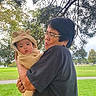 Jiron Caelix is registered to the contest to win money with this photo: baby, infant, child, adult, caregiver, portrait, outdoor, park, grass, trees, family, being_held, bear_costume, fuzzy_clothing, hat, surprised_expression, glasses, smiling, daylight, nature