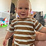 toddler, child, indoor, portrait, smiling, striped_shirt, jeans, pony_tail, playful, toy, living_room, clock, wooden_floor, furniture, person, casual_clothing, happy, young_child, cute, home