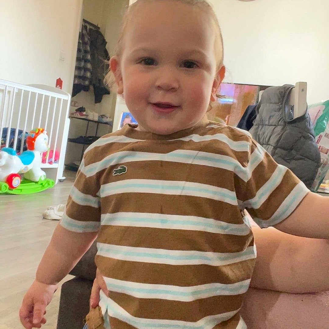 Phärel a rejoint le concours — aidez-le/la à gagner de superbes lots ! casual_clothing, child, clock, cute, furniture, happy, home, indoor, jeans, living_room, person, playful, pony_tail, portrait, smiling, striped_shirt, toddler, toy, wooden_floor, young_child