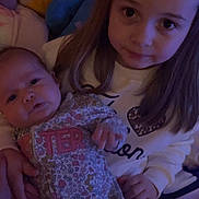 Eliana is registered to the contest to win money with this photo: child, baby, infant, girl, sleepwear, plush_toys, blanket, bed, indoor, portrait, holding, cute, family, sibling, cozy, soft_lighting, smile, person, young, candid