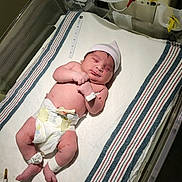 Luna is registered to the contest to win money with this photo: newborn, baby, hospital, bassinet, blanket, diaper, hat, medical, infant, bed, person, sleeping, wristband, ankleband, healthcare, nursery, patient, cute, small, resting