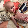 Fiadh is registered to the contest to win money with this photo: baby, smiling, child, play_mat, mirror_toy, pink, striped_dress, embroidery, floor, hand, face, indoor, cute, infant, toy, pattern, colorful, happy, person, toddler