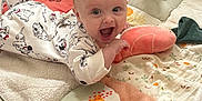 Fiadh is registered to the contest to win money with this photo: baby, infant, onesie, playmat, toy, plush, giraffe_toy, smiling, happy, crawling, indoor, child, cute, soft_toys, floor, blanket, face, person, playtime, home
