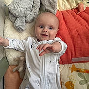 Fiadh is registered to the contest to win money with this photo: baby, smiling, onesie, plush_toy, bunny, blanket, colorful, reaching_hand, infant, indoor, soft_toys, play_area, cute, lying_down, child, happy, face, pajamas, cozy, comfort