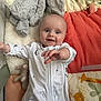 baby, smiling, onesie, plush_toy, bunny, blanket, colorful, reaching_hand, infant, indoor, soft_toys, play_area, cute, lying_down, child, happy, face, pajamas, cozy, comfort