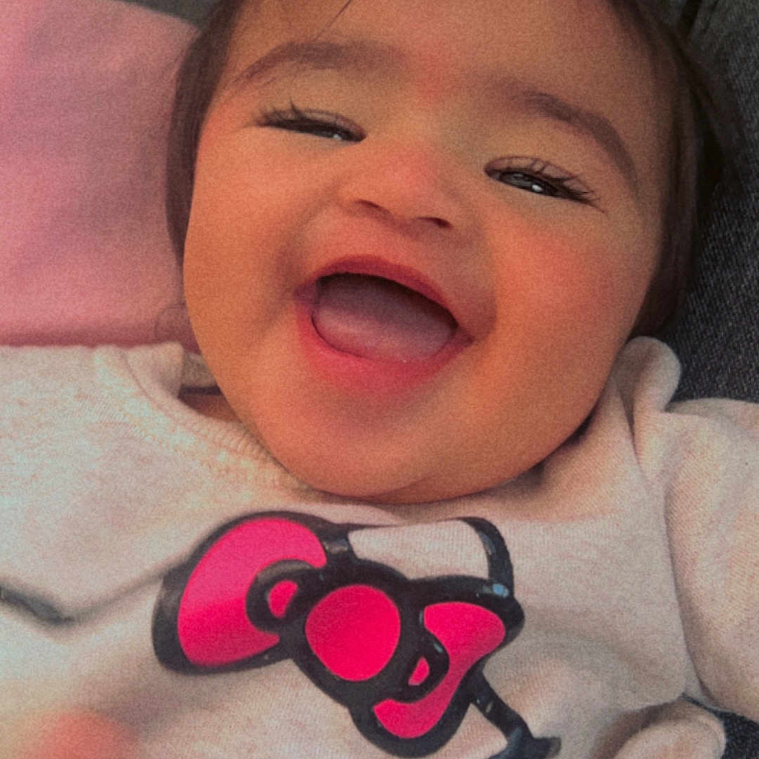 Janella is registered to the contest to win money with this photo: apparel, baby, cartoon, child, closeup, clothing, cute, expression, face, happy, indoor, infant, joyful, person, pink, portrait, smiling, sweater, toddler, young