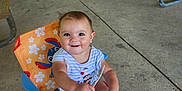 Ivory is registered to the contest to win money with this photo: baby, child, smiling, sitting, chair, sunglasses, pavilion, picnic_tables, concrete_floor, outdoor, clothing, happy, person, infant, playful, colorful, summer, casual, cute, daylight