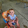 baby, child, smiling, sitting, chair, sunglasses, pavilion, picnic_tables, concrete_floor, outdoor, clothing, happy, person, infant, playful, colorful, summer, casual, cute, daylight
