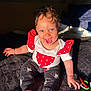 baby, child, smiling, curly_hair, blue_eyes, sitting, clothing, red, white, polka_dot, pants, mickey_mouse, foot, hand, blanket, sunlight, indoor, happy, cute, portrait