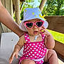 Leyna a rejoint le concours — aidez-le/la à gagner de superbes lots ! baby, child, sunglasses, hat, polka_dot, swimsuit, pink, white, outdoor, sunlight, wooden_railing, hand, skin, cute, summer, shade, nature, greenery, seat, relaxing