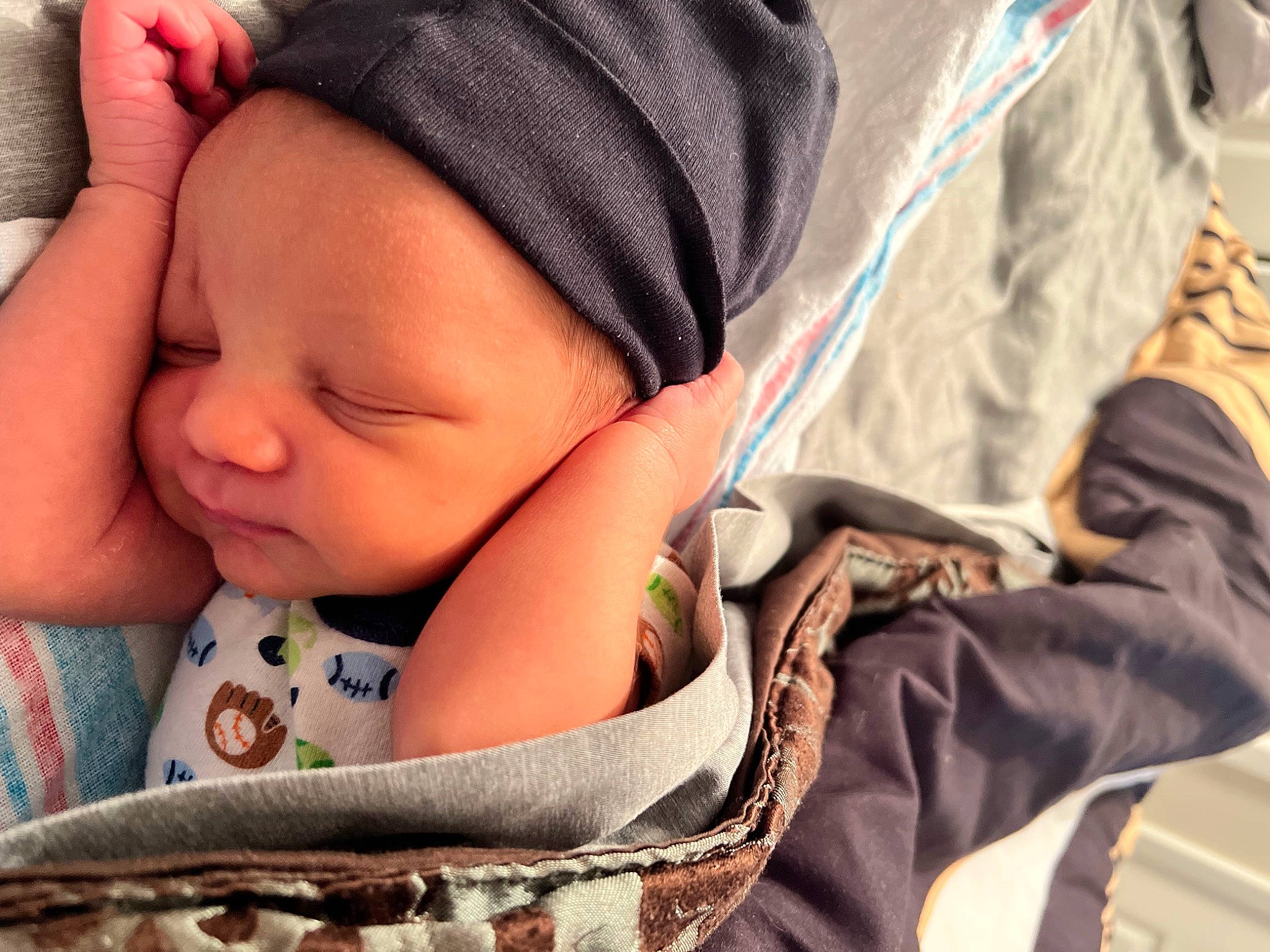 Zahkai is registered to the contest to win money with this photo: baby, baby_sleeping, baby_toddler_clothing, cap, cheek, child, close_up, comfort, face, facial_expression, happy, headgear, linens, mouth, pattern, person, sitting, skin, sleeve, textile