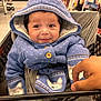 baby, child, smiling, hood, blue_sweater, shopping_cart, hand, indoor, clothing, cute, face, infant, warm, pattern, store, retail, baby_clothes, person, happy, portrait