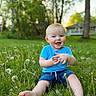toddler, child, grass, dandelion, outdoor, nature, blue_shirt, denim_shorts, barefoot, happy, smiling, sitting, greenery, sunset, house, tree, playful, cute, young_child, sunlight