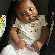 Jaylani joined the competition — help win amazing prizes! baby, child, car_seat, infant, sitting, clothing, pajamas, face, eyes, hands, safety_label, indoors, portrait, cute, young, person, expression, seat, head, cozy