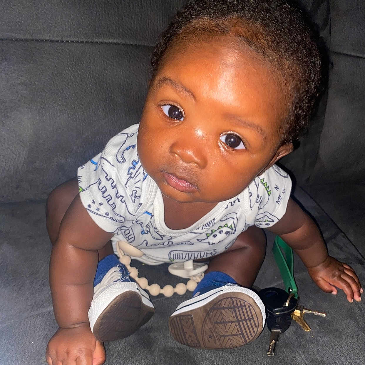 Jobari is registered to the contest to win money with this photo: baby, child, closeup, couch, curious, expression, eyes, face, flash, furniture, hand, indoor, infant, keys, onesie, person, seated, skin, sneakers, toy