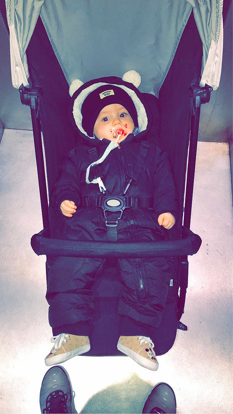Timéo participe au concours pour gagner de l'argent avec cette photo : baby, child, stroller, snowsuit, hat, pacifier, shoes, floor, indoor, person, winter_clothing, pom_poms, black_clothing, footwear, baby_shoes, face, wide_eyes, infant, casual, portrait