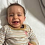 Winston is registered to the contest to win money with this photo: baby, smiling, happy, infant, face, clothing, striped, cute, child, portrait, hand, lying_down, toddler, indoors, expression, young, skin, hair, cozy, soft