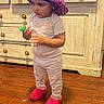 child, toddler, standing, portrait, kitchen, cabinets, wooden_floor, bonnet, leopard_print, red_boots, pajamas, toy, pacifier, curious, indoors, home, furniture, fashion, full_body, photography