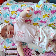 Miciah is registered to the contest to win money with this photo: baby, infant, child, blanket, bunny_pattern, headband, pink_clothing, bottle, quilt, fabric, smile, portrait, lying_down, arm, hand, bed, nursery, cute, colorful, soft_texture