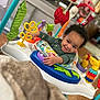Sadon joined the competition — help win amazing prizes! baby, child, smile, curly_hair, activity_center, toy, colorful, indoor, play, happy, infant, clothing, face, hand, seat, furniture, room, blurred_background, expression, person