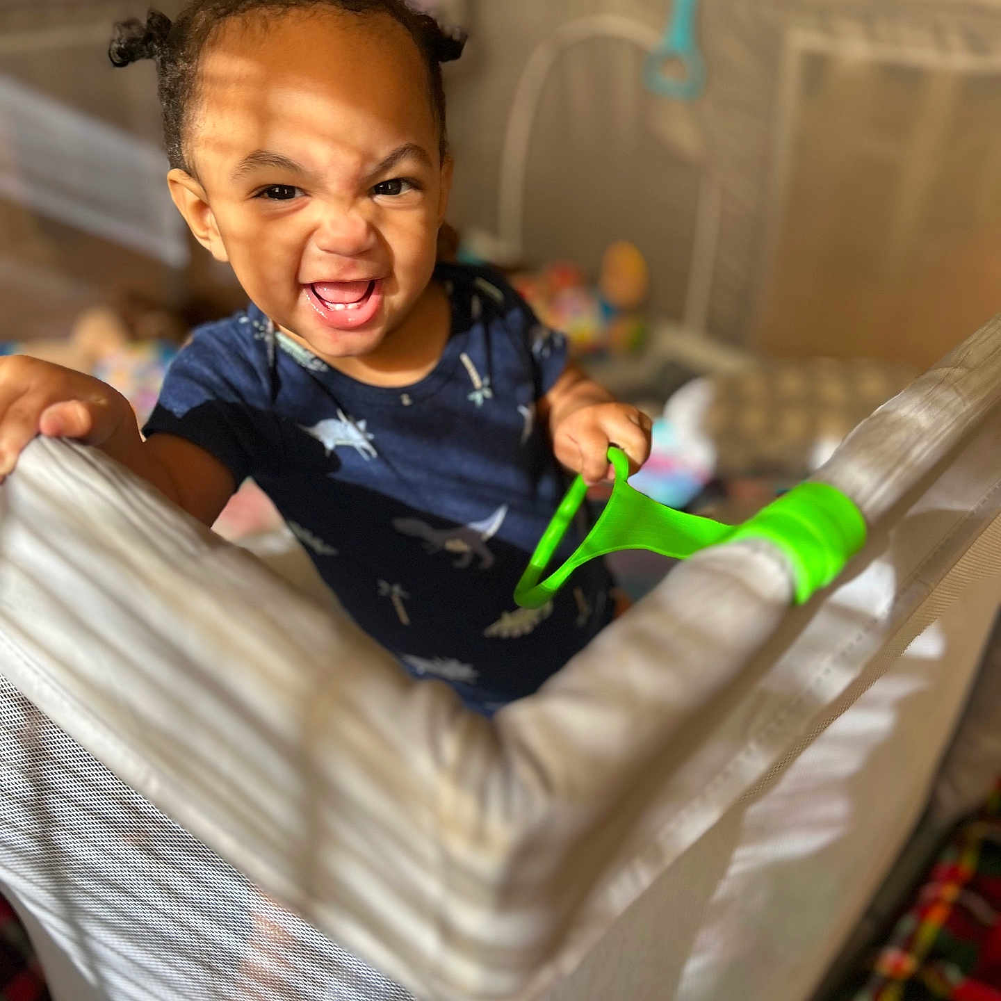 Sadon is registered to the contest to win money with this photo: baby, child, clothing, colorful, expression, furniture, grip, hair, happy, indoor, light, mesh, person, play, playpen, room, shadow, smile, toddler, toy