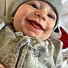 baby, smile, face, hat, clothing, person, infant, happy, beanie, patterned_clothing, portrait, cute, indoor, casual, child, apparel, closeup, headwear, young, holding