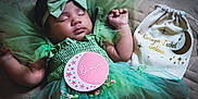 Karaya is registered to the contest to win money with this photo: baby, sleeping, green_dress, headband, bow, milestone_card, one_month, quilted_blanket, decorative_bag, name_tag, infant, cute, portrait, tulle, soft_lighting, peaceful, hands_up, closeup, newborn, indoor
