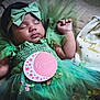 baby, sleeping, green_dress, headband, bow, milestone_card, one_month, quilted_blanket, decorative_bag, name_tag, infant, cute, portrait, tulle, soft_lighting, peaceful, hands_up, closeup, newborn, indoor