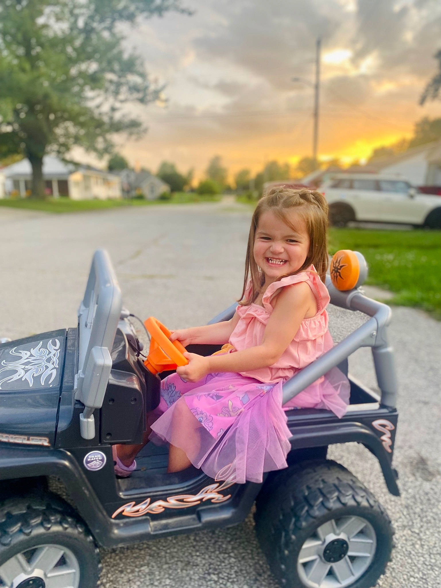Paisley is registered to the contest to win money with this photo: automotive_design, automotive_tire, car, cloud, dress, grass, happy, joy, light, motor_vehicle, orange, person, pink, plant, riding_toy, sky, smile, tire, tread, tree