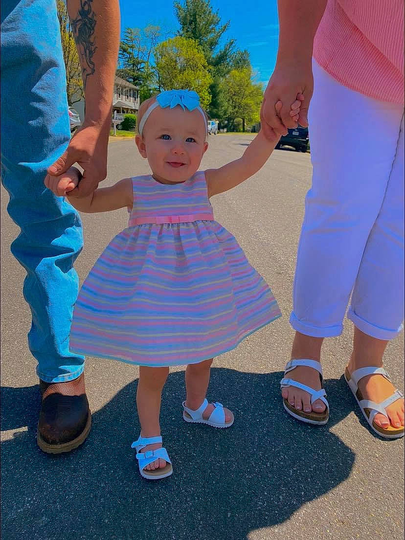 Hartley Grace Barnes is registered to the contest to win money with this photo: aqua, azure, baby_toddler_clothing, blue, dress, fashion, footwear, fun, gesture, happy, holding_hands, joint, joy, person, pink, product, shoe, shoulder, sky, sleeve