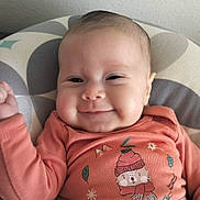 Céline participe au concours pour gagner de l'argent avec cette photo : baby, infant, smile, face, clothing, cushion, pattern, peach, cute, cheeks, portrait, child, cozy, apparel, young, indoors, happy, person, lying_down, expression