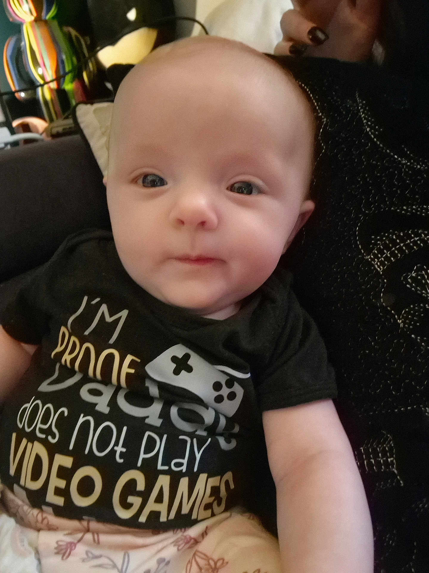 Eliana is registered to the contest to win money with this photo: baby, infant, child, person, face, eyes, shirt, text, hand, sitting, indoors, clothing, cute, portrait, young, human, expression, comfort, parent, humor