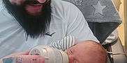 Eliana is registered to the contest to win money with this photo: baby, beard, blanket, bottle, care, closeup, clothing, comfort, face, feeding, hand, hat, holding, indoor, love, man, person, sleeping, tattoo, together
