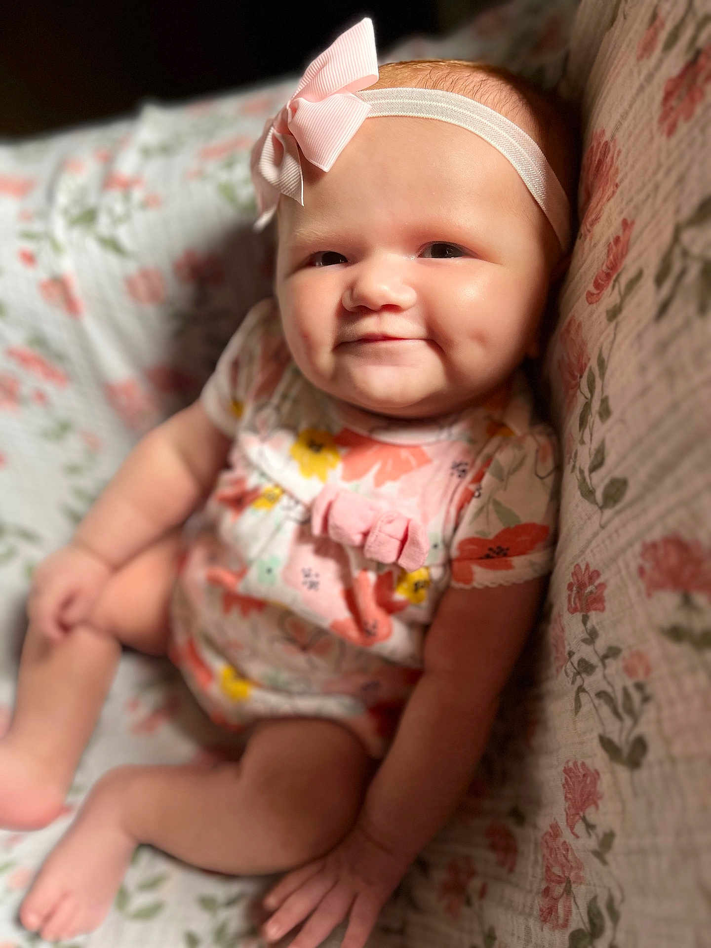Amelia joined the competition — help win amazing prizes! baby, infant, smiling, dimple, headband, bow, onesie, floral, pattern, quilt, seated, cute, child, skin, face, hand, foot, indoors, portrait, happy
