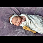 Ayvalynn joined the competition — help win amazing prizes! newborn, baby, sleeping, blanket, headband, wooden_brush, purple_blanket, infant, wrapped, soft_texture, peaceful, cute, portrait, resting, indoors, closeup, child, person, tender, cozy